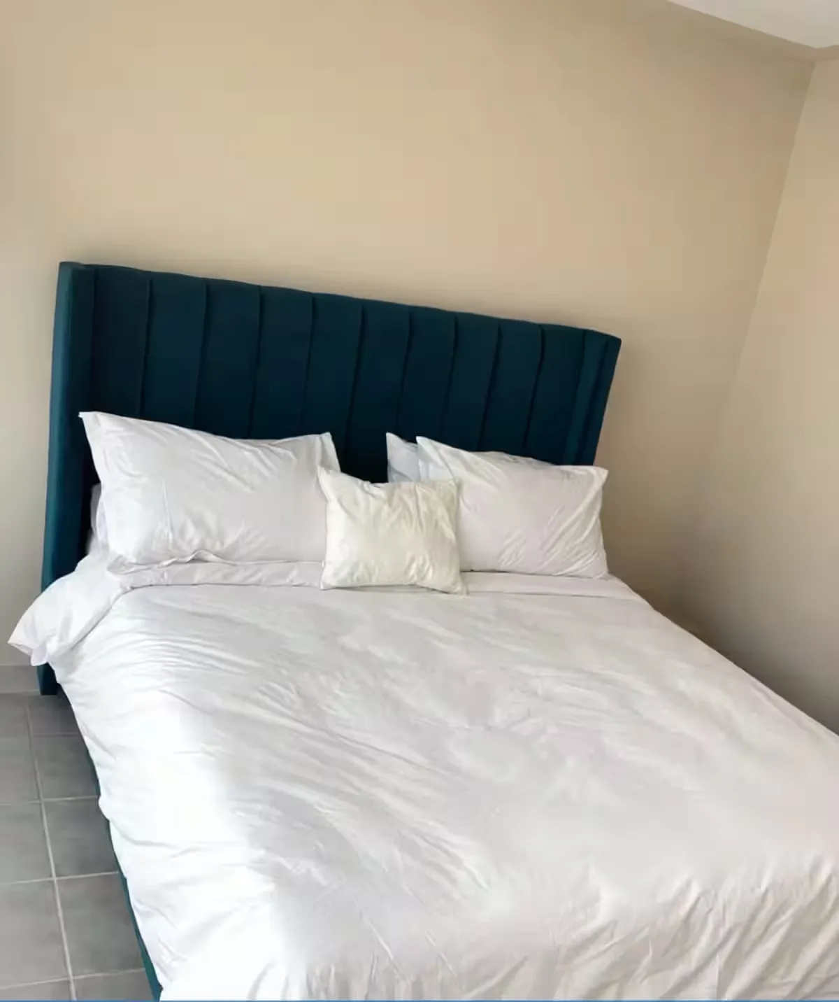 Comfortable double bed with deep teal velvet headboard at Ciel Studio