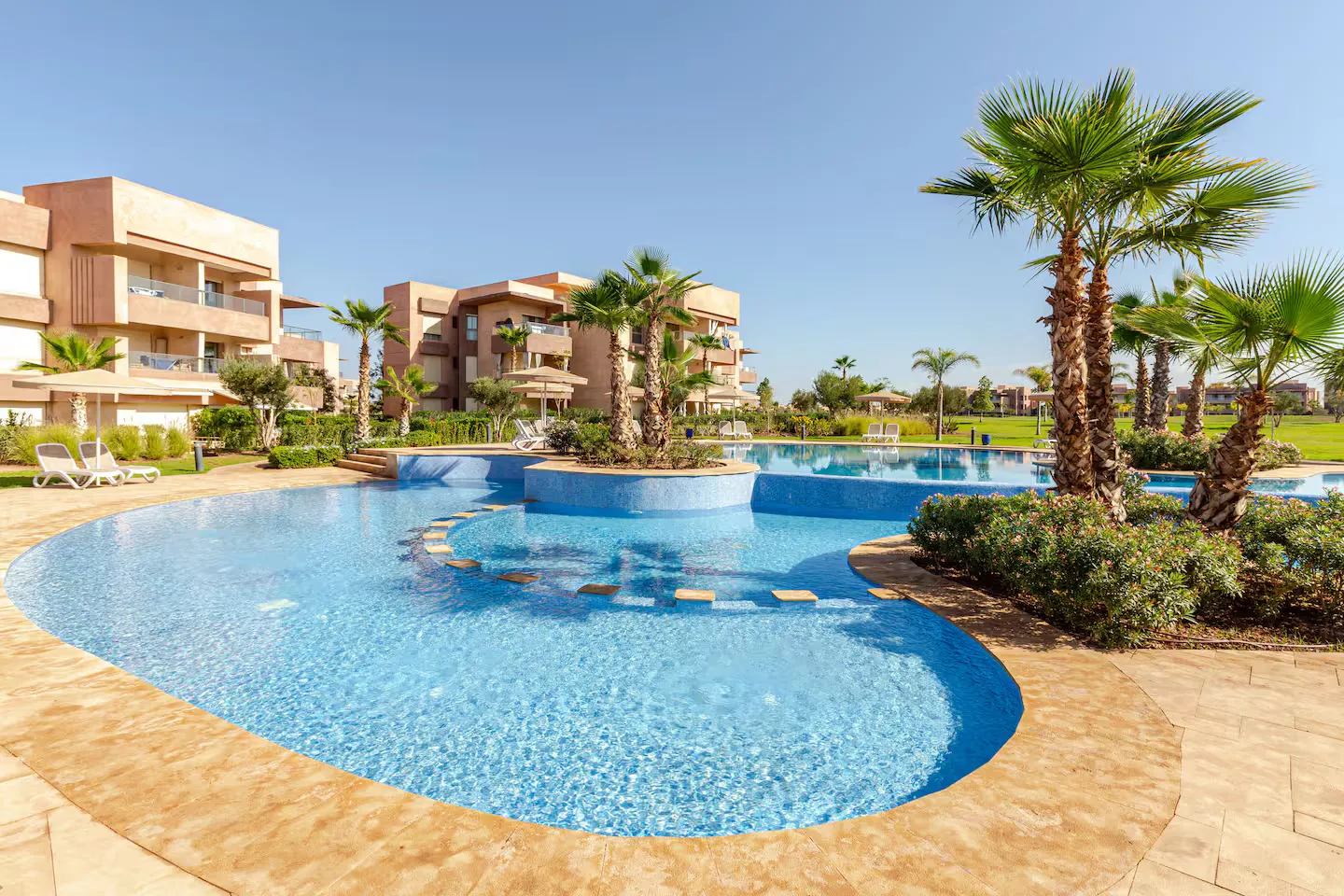 Lagoon swimming pool surrounded by palm trees and gardens at Prestigia Saphir palm grove apartment