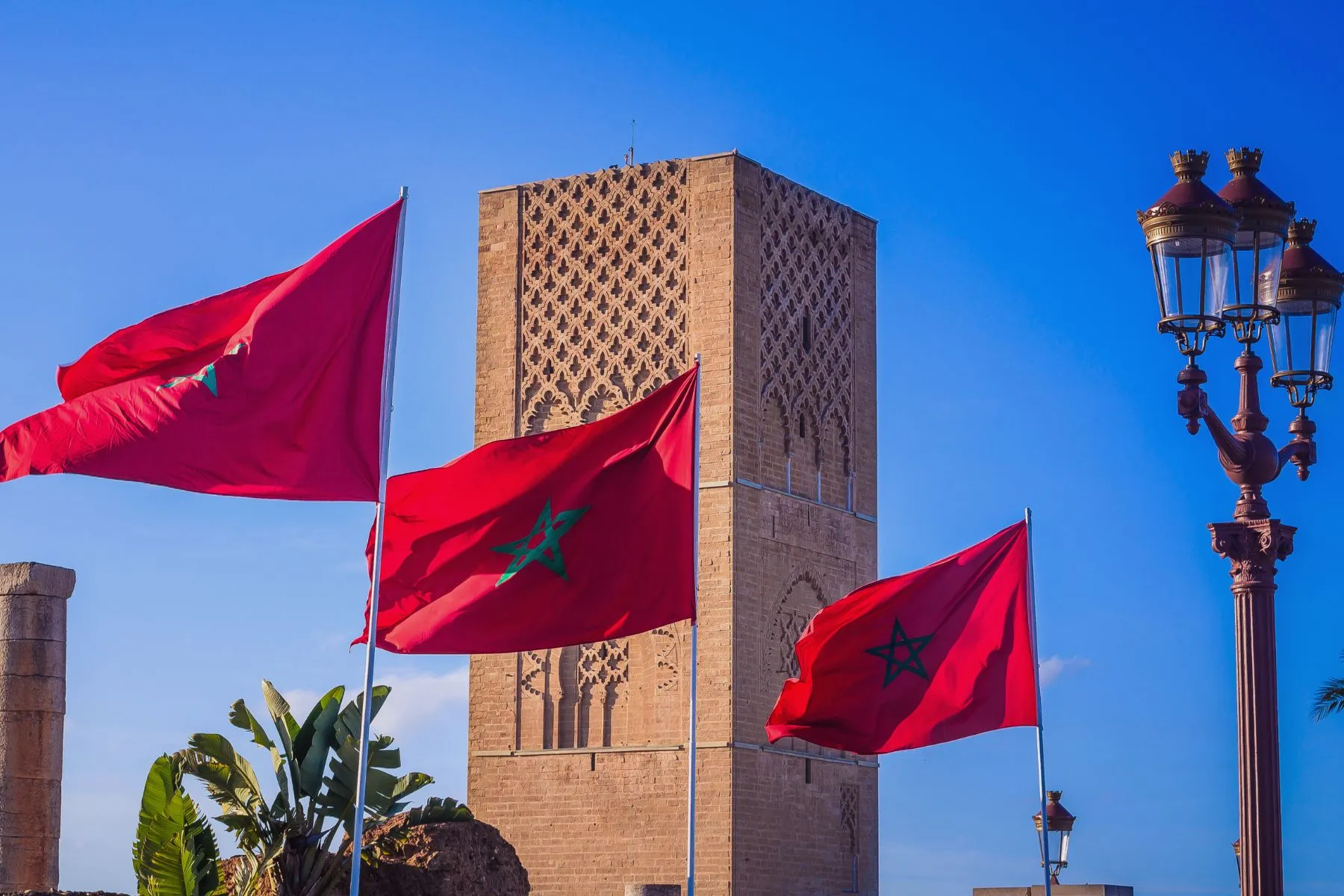 Moroccan red flags waving in front of historic architecture, showcasing the best cities to visit in Morocco