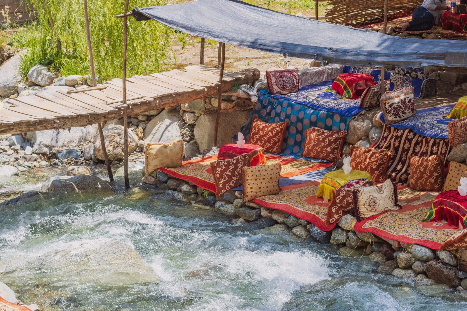 Riverside restaurant seating with traditional cushions along the riverbank in Ourika Valley