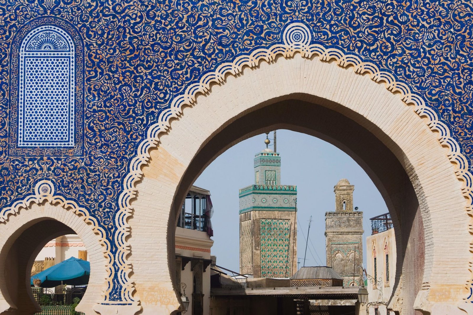 Minaret de Fès aperçu à travers l'arche en zellige bleu emblématique de Bab Bou Jeloud
