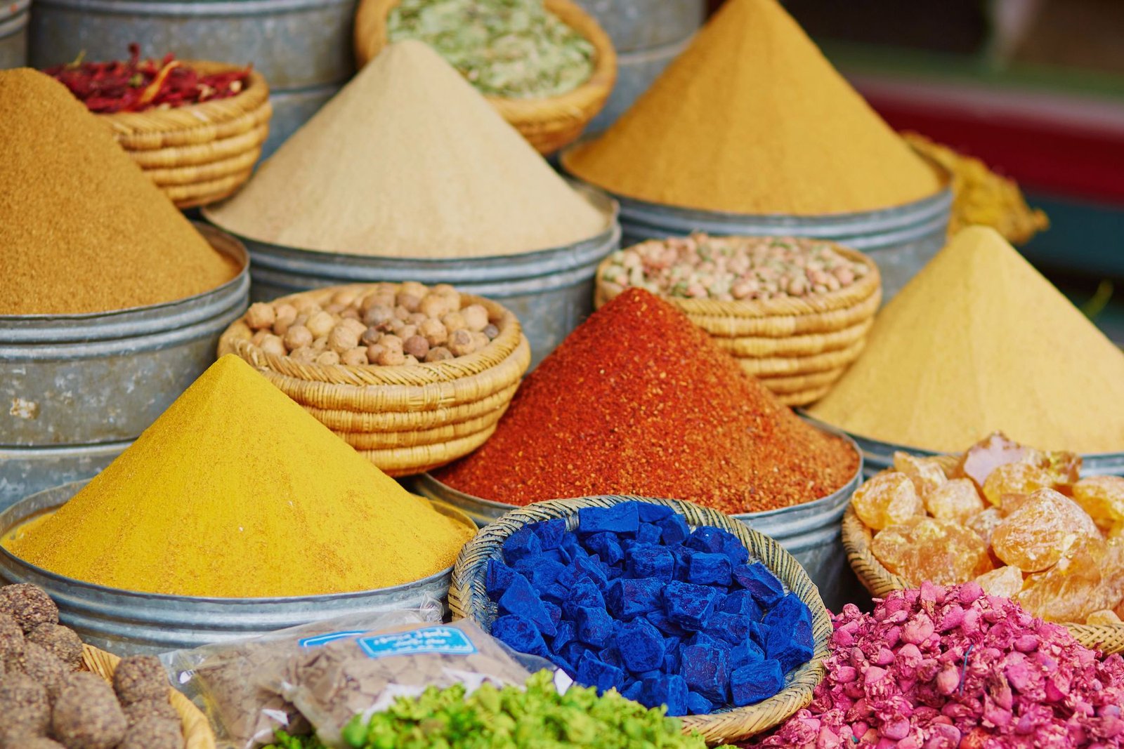 Épices marocaines colorées présentées en pyramides dans un souk traditionnel