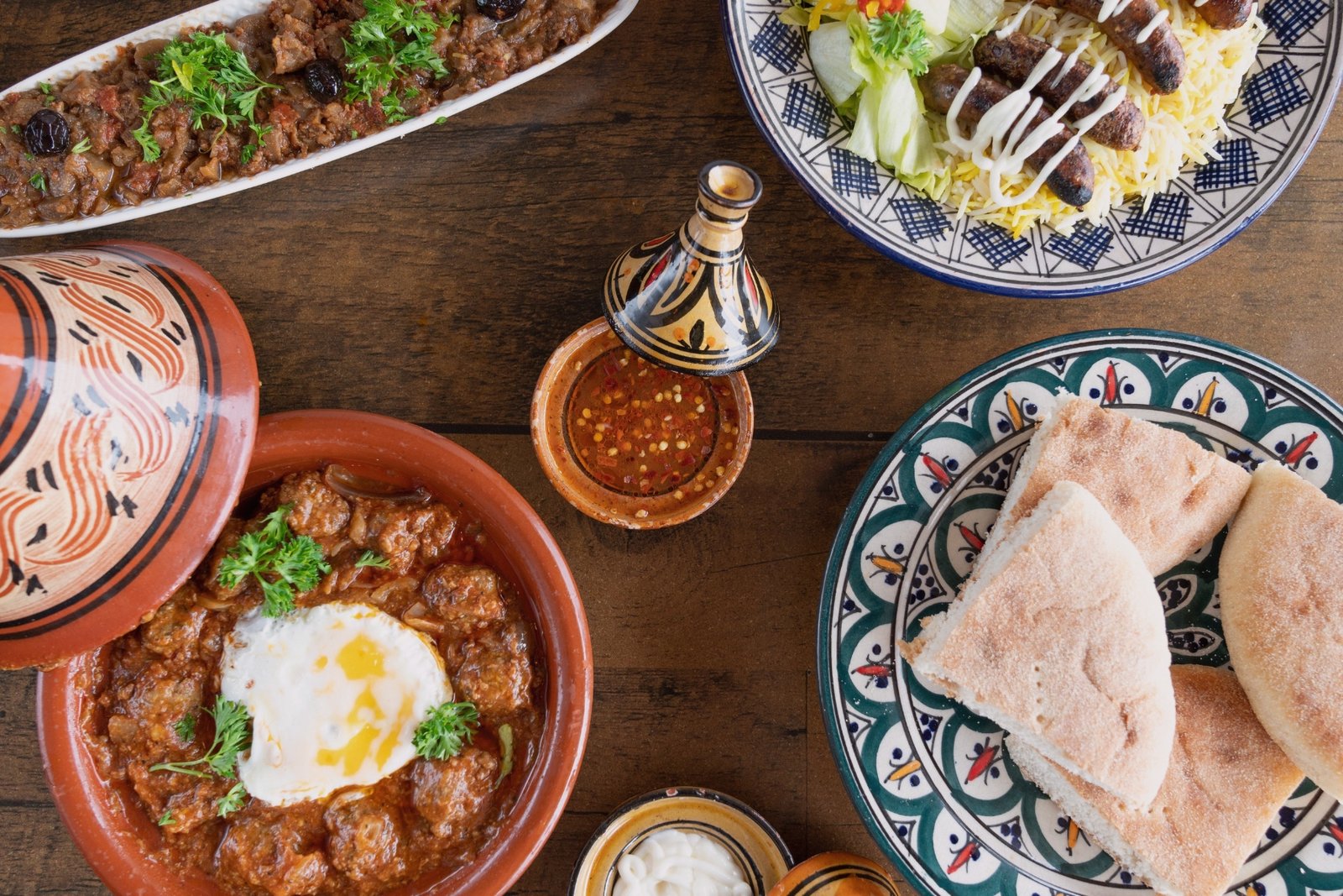 Table garnie de plats traditionnels marocains avec tajine de kefta, pain khobz et salades