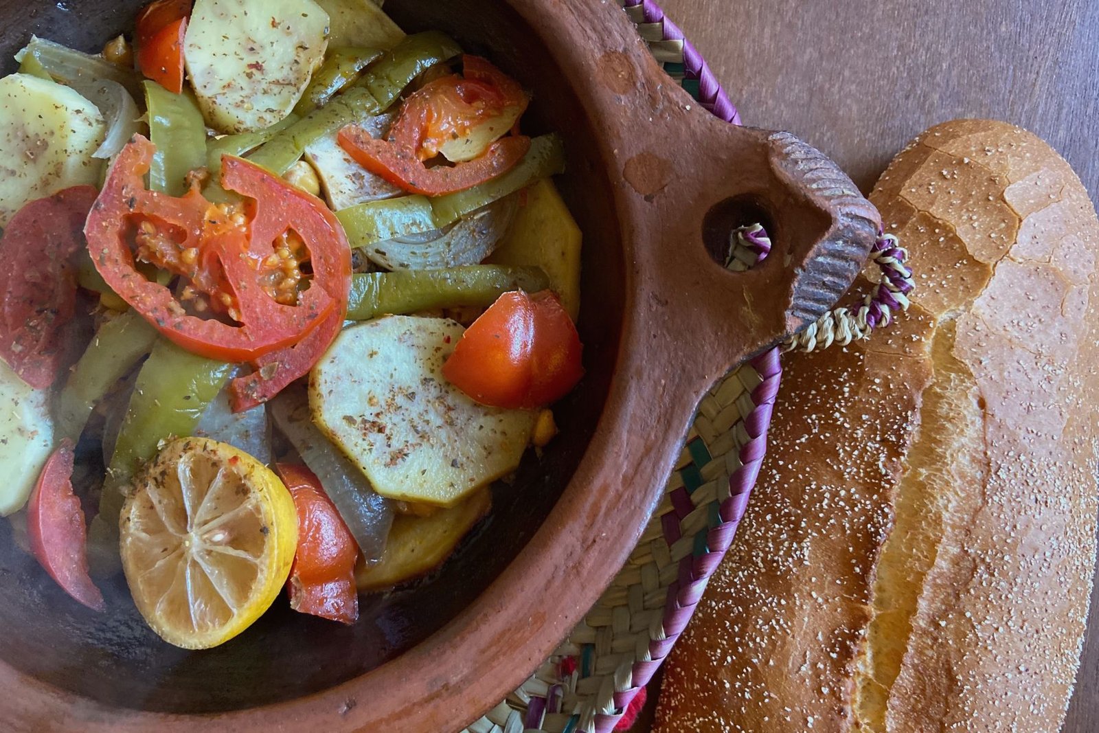 Traditional Moroccan vegetable tagine with preserved lemons served alongside fresh bread