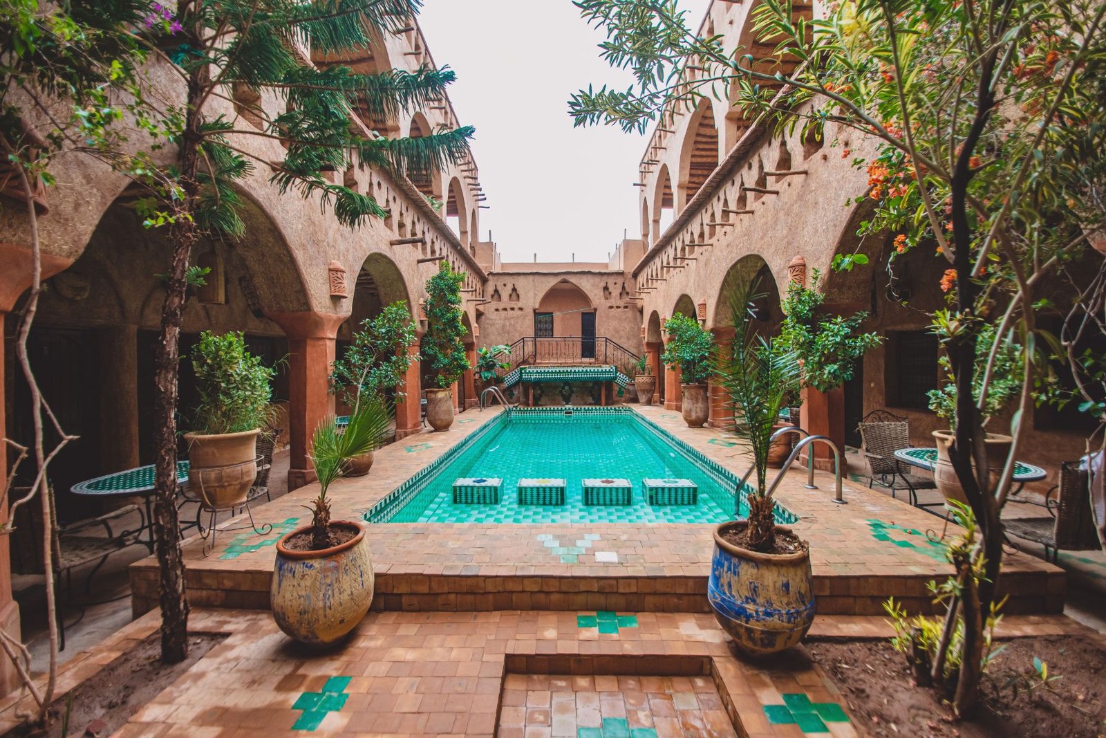 Spacious courtyard pool surrounded by arches and lush plants in a traditional Moroccan house